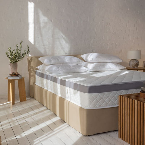 Matratzen Bundle mit Taschenfederkernmatratze und federfreiem Topper auf modernem Bettgestell in einem hellen Schlafzimmer.