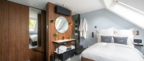 Modernes Hotelzimmer mit hochwertigem Doppelbett, weißen Bettwaren, eleganten Holzelementen, offenem Waschbereich und stilvollem Design für ein komfortables Luxushotel-Ambiente.