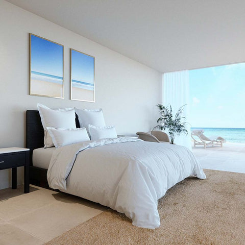 Elegantes weißes Boxspringbett mit weicher Bettwäsche und stilvollen Kissen in modernem Schlafzimmer mit Blick auf das Meer
