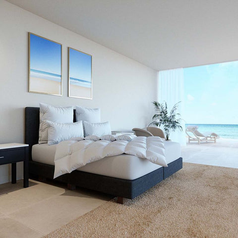 Luxuriöse Eiderdaunendecke auf modernem Bett in hellem Schlafzimmer mit Meerblick und hochwertiger Hotelatmosphäre