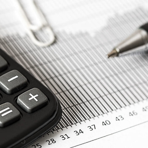 Schreibtisch mit Taschenrechner, Stift und Finanzunterlagen