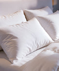 Mehrere HANSE Premium Natural Hybrid Kissen im Sonnenlicht am Kopfteil eines Hotelbetts