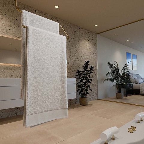 Zwei weiche, weiße Premium Badetücher, die elegant über die Sprossen einer dekorativen Holzleiter im Badezimmer gehängt sind, neben einer grünen Zimmerpflanze.